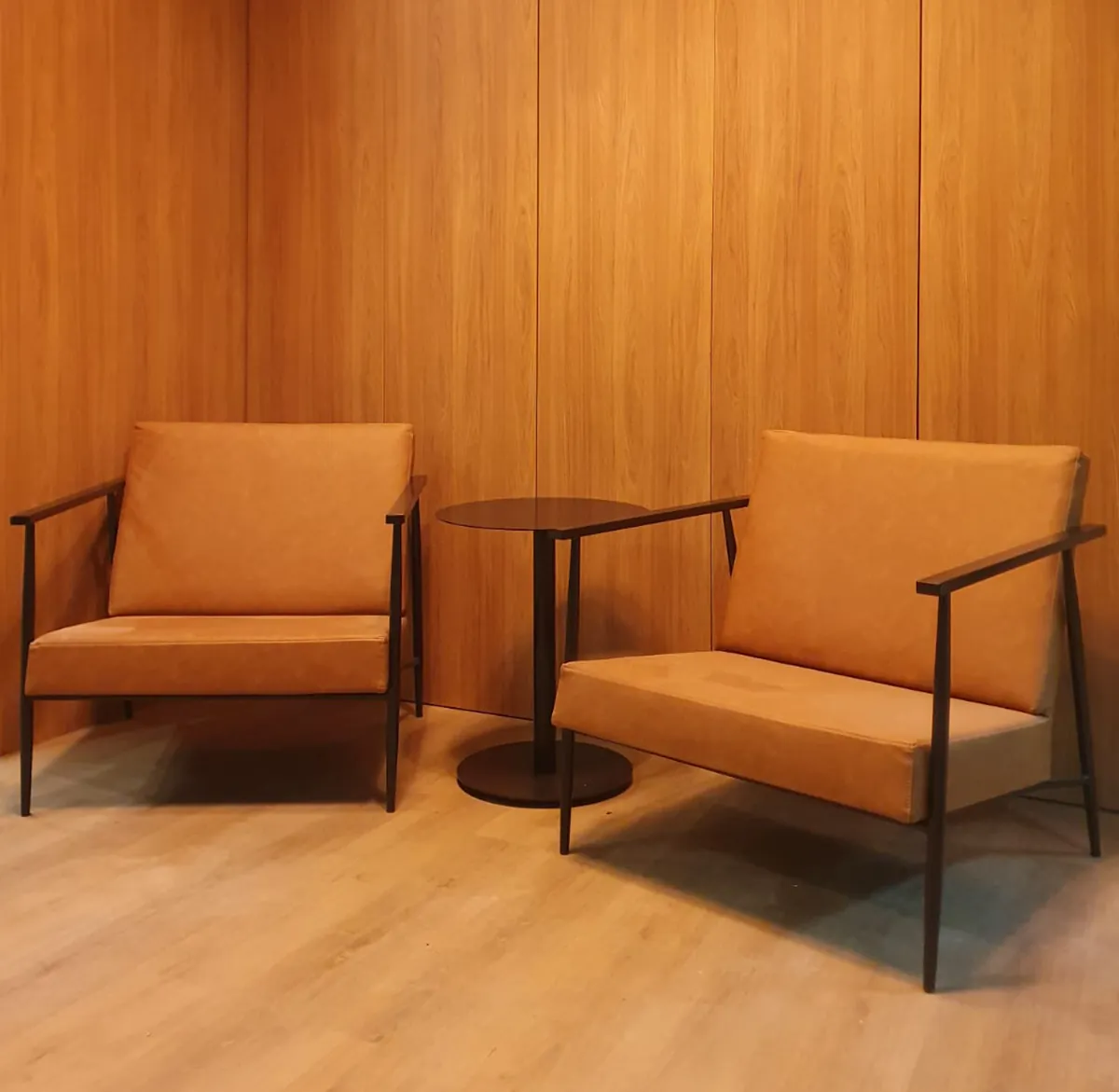 Poltronas de couro com estrutura metálica em recepção corporativa